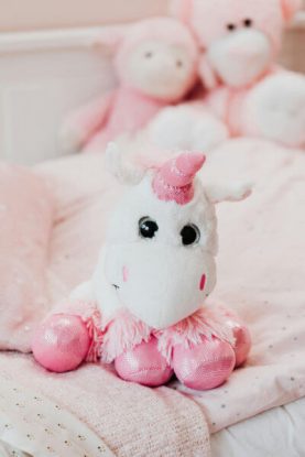 Declutter toys like this unicorn stuffed animal on a child's bed with your kids